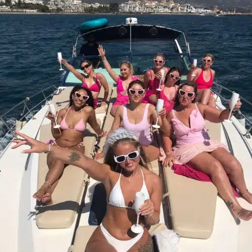 A Marbella boat party group dancing with drinks in hand under the sun