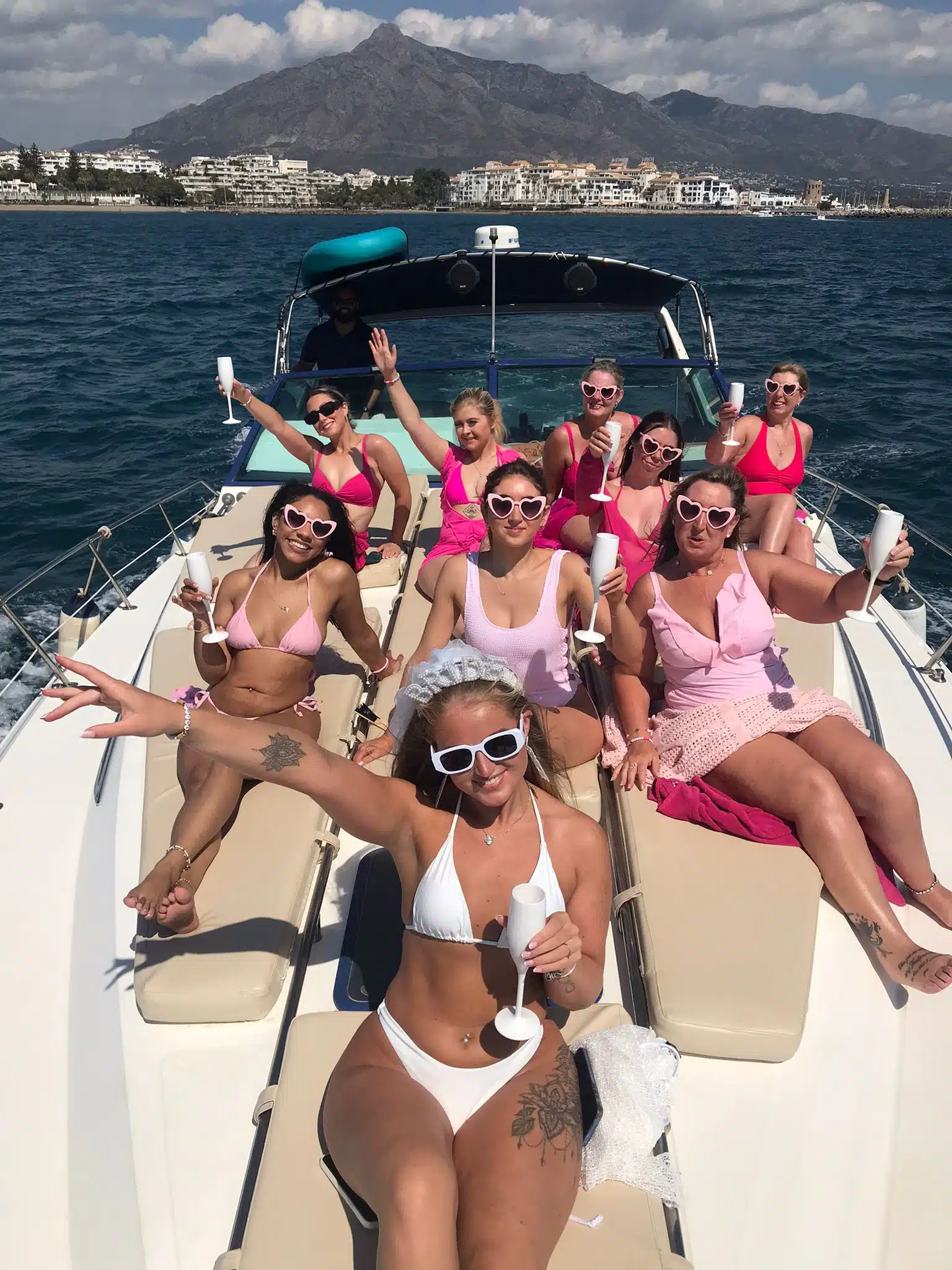 A Marbella boat party group dancing with drinks in hand under the sun